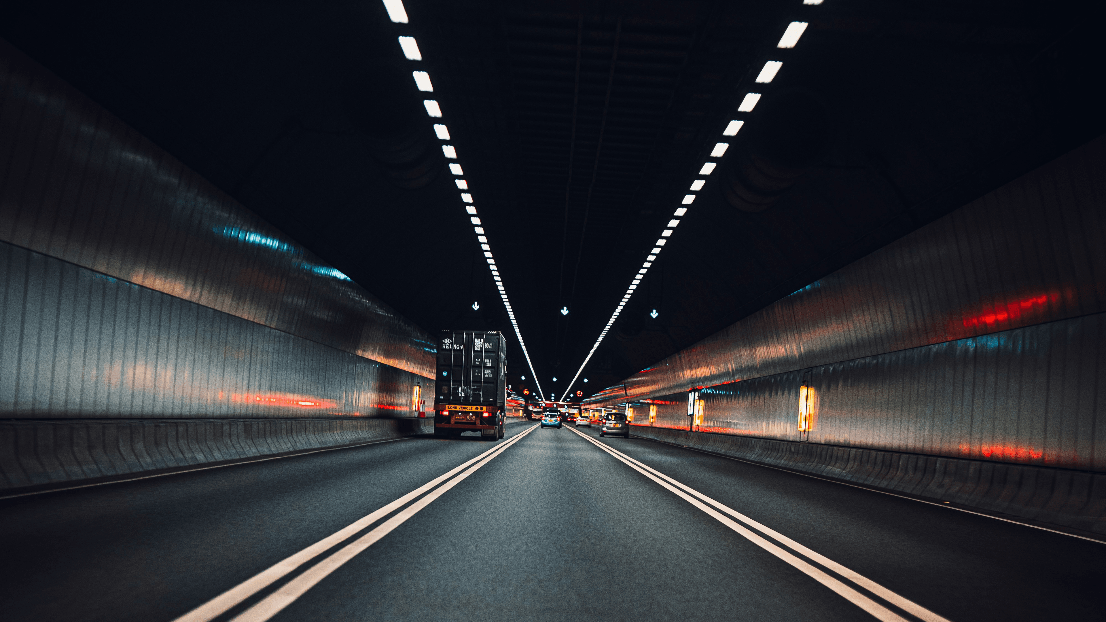 Container truck driving through a highway tunnel at night